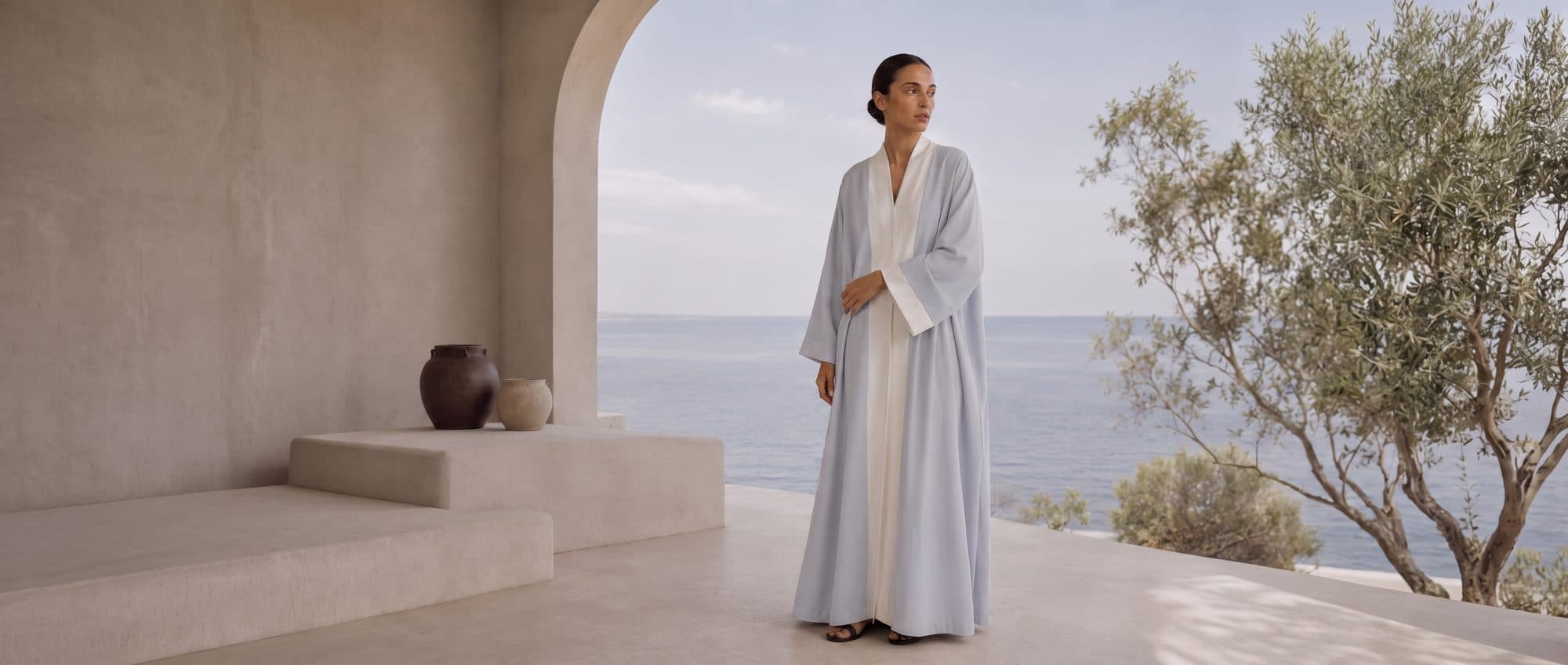 A pale abaya against a whitewashed terrace, the sea beyond